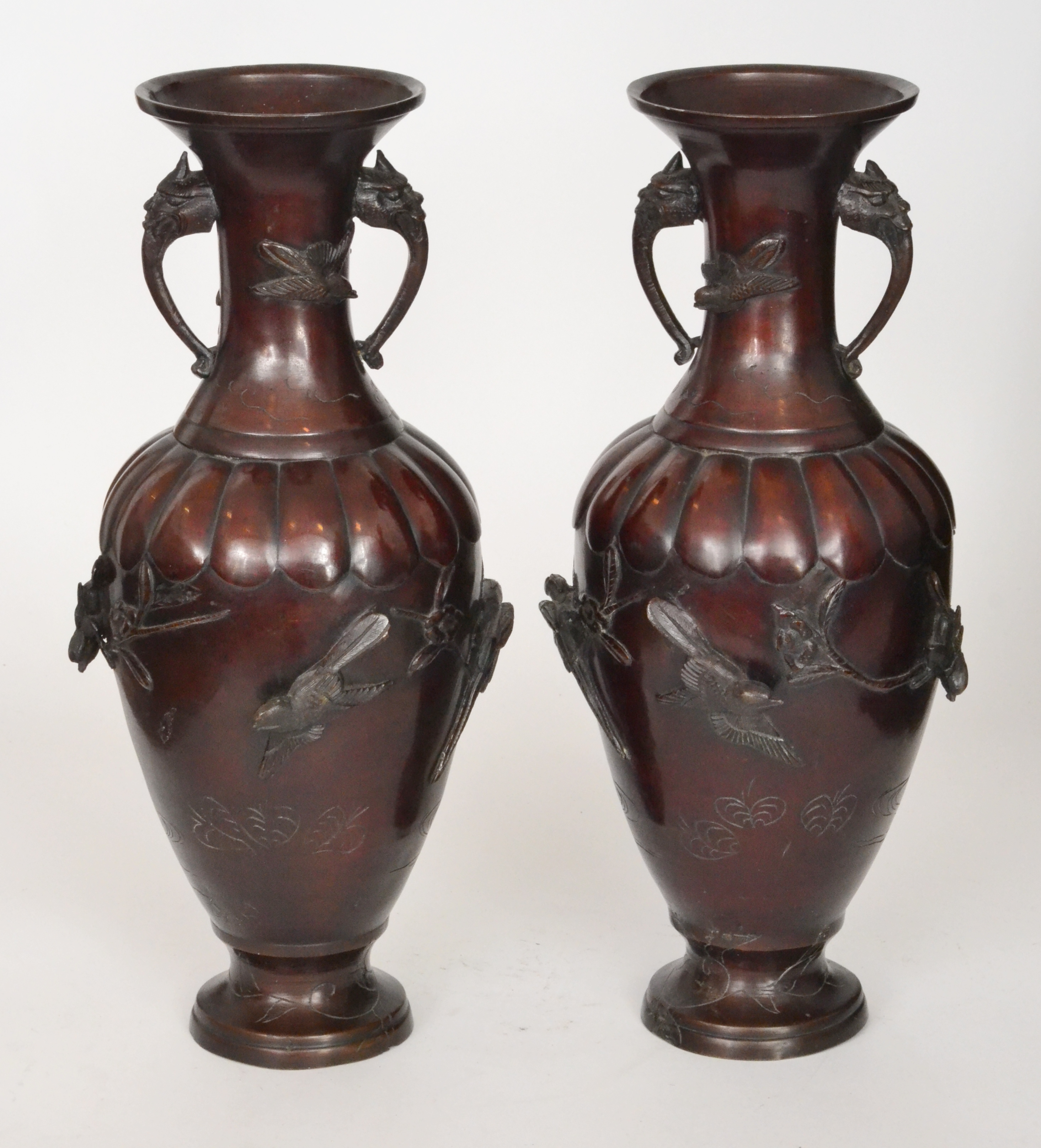 A pair of Meiji period bronze baluster twin handled vases each decorated with relief moulded birds
