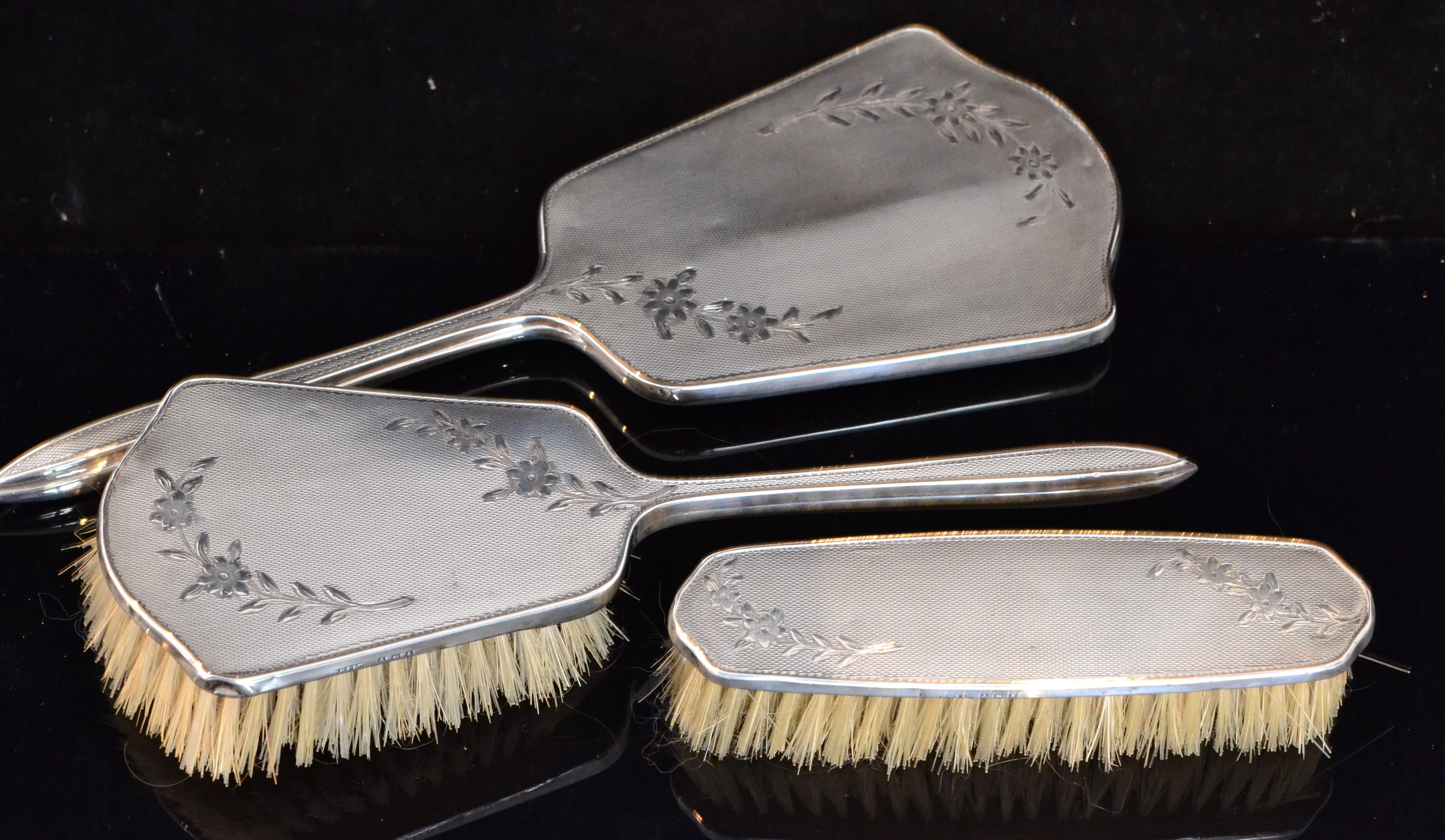 A mid 20th Century hallmarked silver backed three piece dressing table set of shaped shield profile,