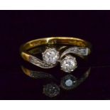 An 18ct diamond two stone cross over ring, brilliant cut stones to diamond set shoulders,