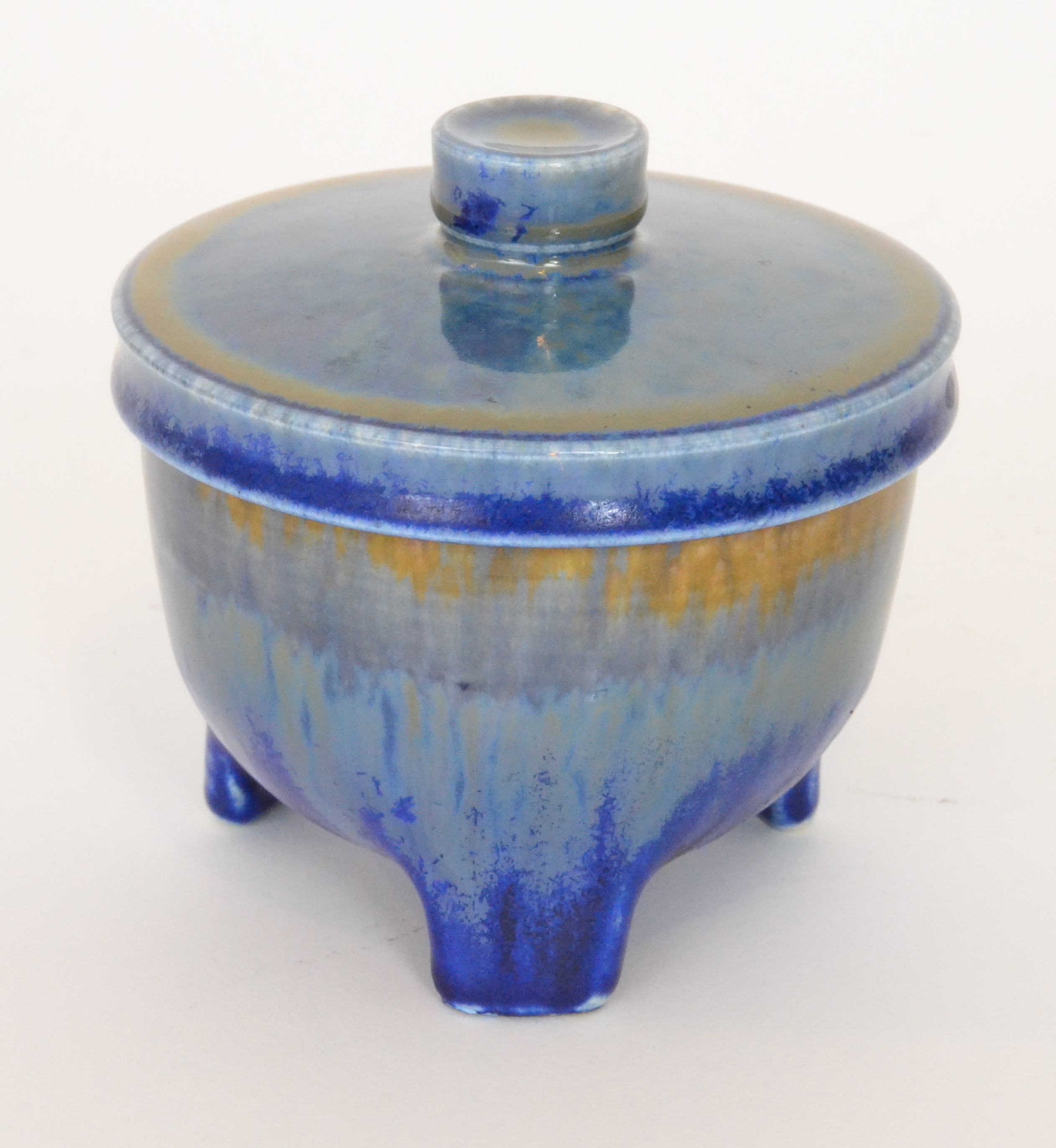 A Ruskin Pottery tri-footed vase and cover decorated in a tonal blue crystalline glaze,