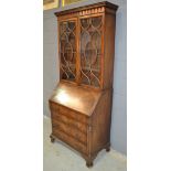 A George III style mahogany bureau bookcase enclosed by a pair of bar glazed doors below a dentil