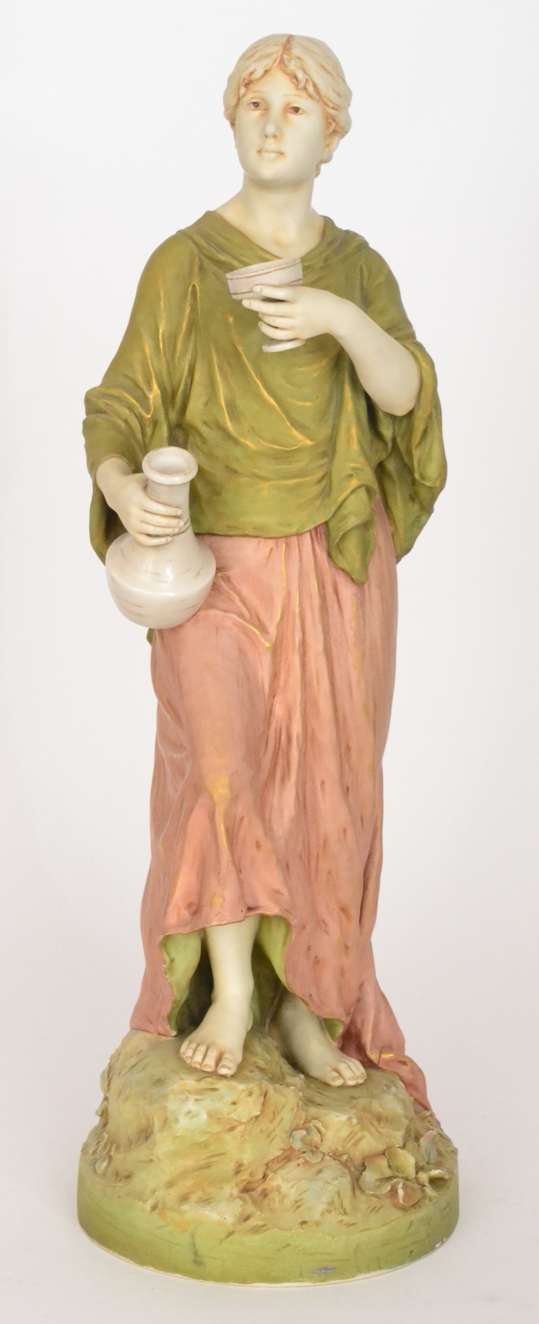 A large Royal Dux Bohemia figure of a lady dressed in green and soft red robes holding a carafe and