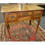 A George III oak and mahogany crossbanded lowboy fitted with three drawers above a shaped apron on