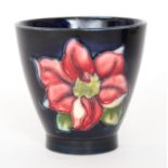 A Moorcroft 'egg-cup' vase decorated in the Clematis pattern with tubelined flowers against a dark