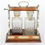 An Edwardian oak two divisioned tantalus fitted with two press moulded decanters on a stepped base,