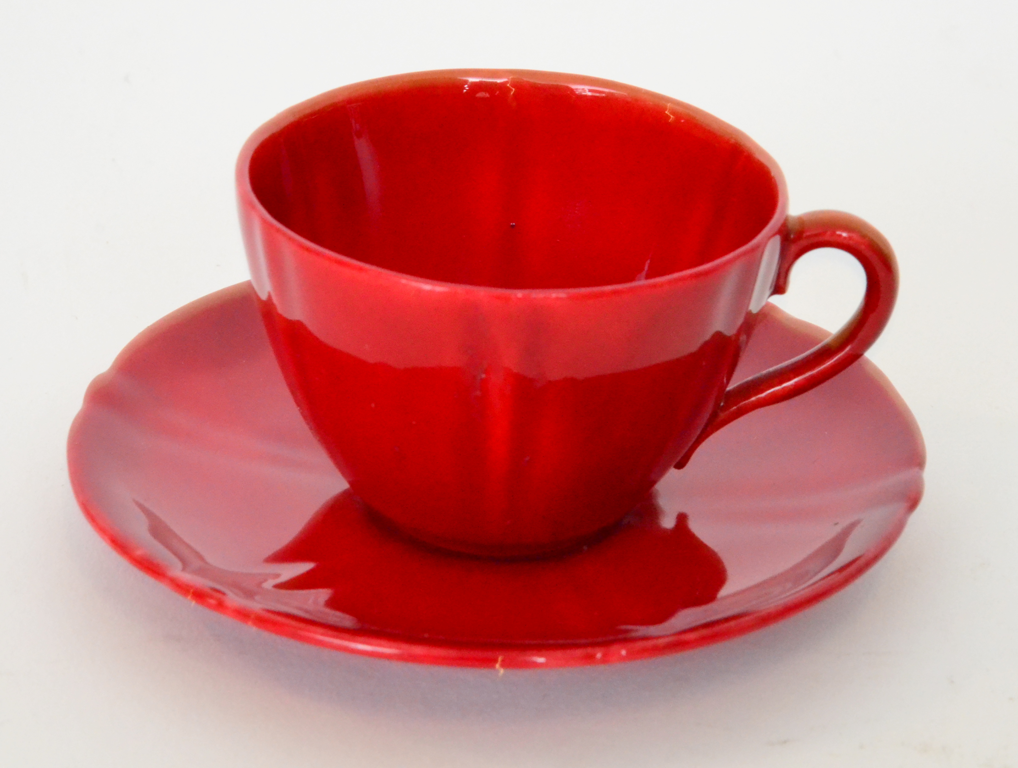 A Royal Doulton Flambe teacup and saucer decorated in a red glaze, printed marks,