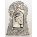 An Art Nouveau embossed white metal photograph frame decorated with winged sphinxes above a green