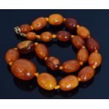 An amber single row bead necklace formed of twenty one graduated varicoloured oval shaped beads,