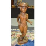 A 20th Century carved floorstanding figure of a cross legged female wearing a bicorn hat and