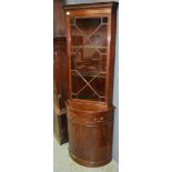 A Georgian style reproduction mahogany bowfront floorstanding corner cabinet enclosed by an