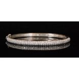 A modern white metal and diamond encrusted hinged bangle with figure of eight safety catch,