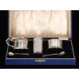A George V hallmarked silver cased three piece condiment set of faceted form, total weight 3.