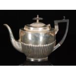 A hallmarked silver boat shaped teapot with part fluted decoration terminating in ebonised handle,