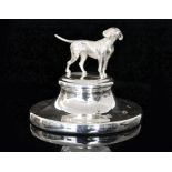 A modern hallmarked silver paperweight, the circular base mounted with a model of a hound,