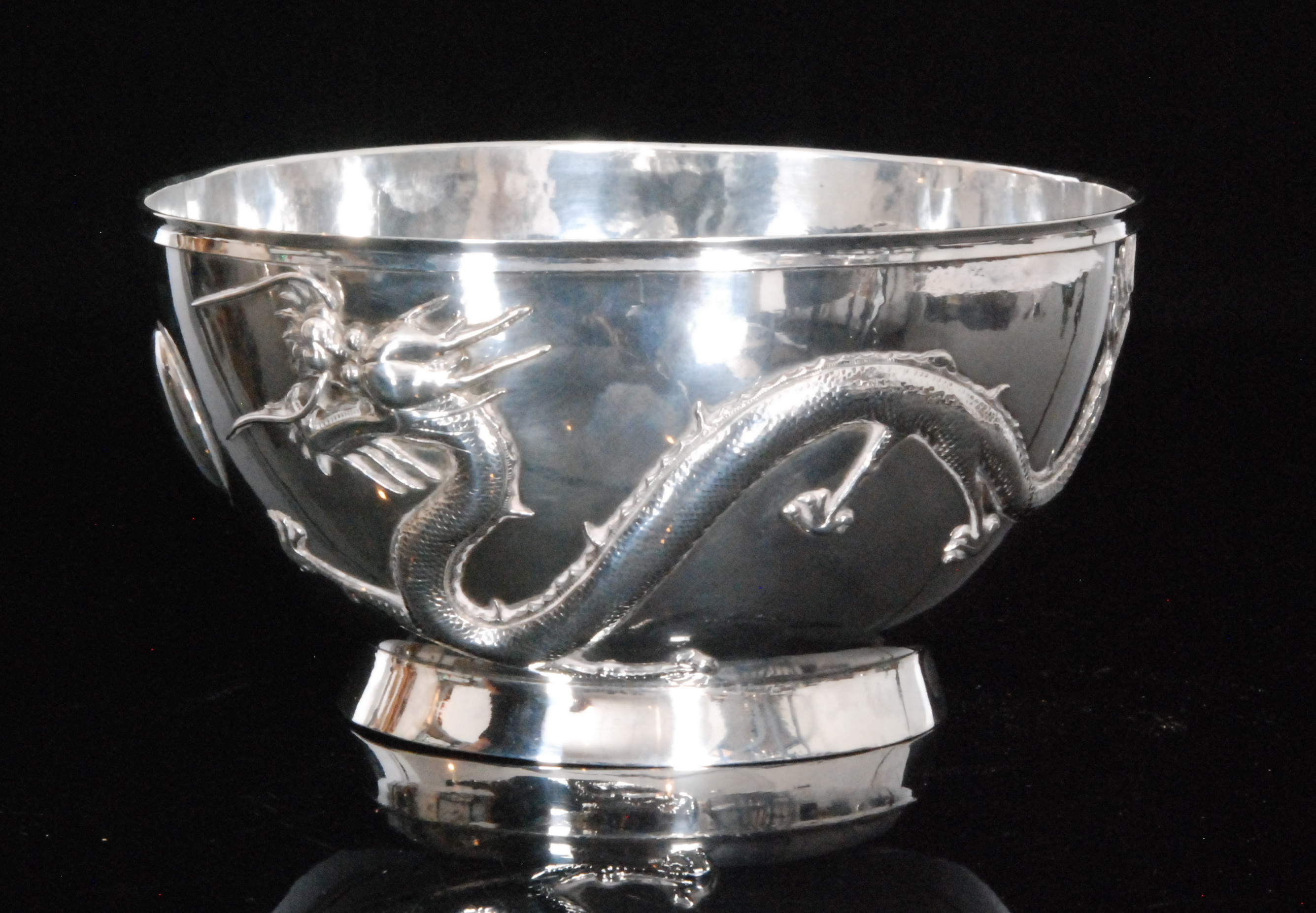 A Chinese silver rose bowl with cast decoration of two scrolling dragons chasing a pearl on