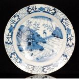 A late 18th Century English tin glazed charger decorated with a Chinese style landscape with a