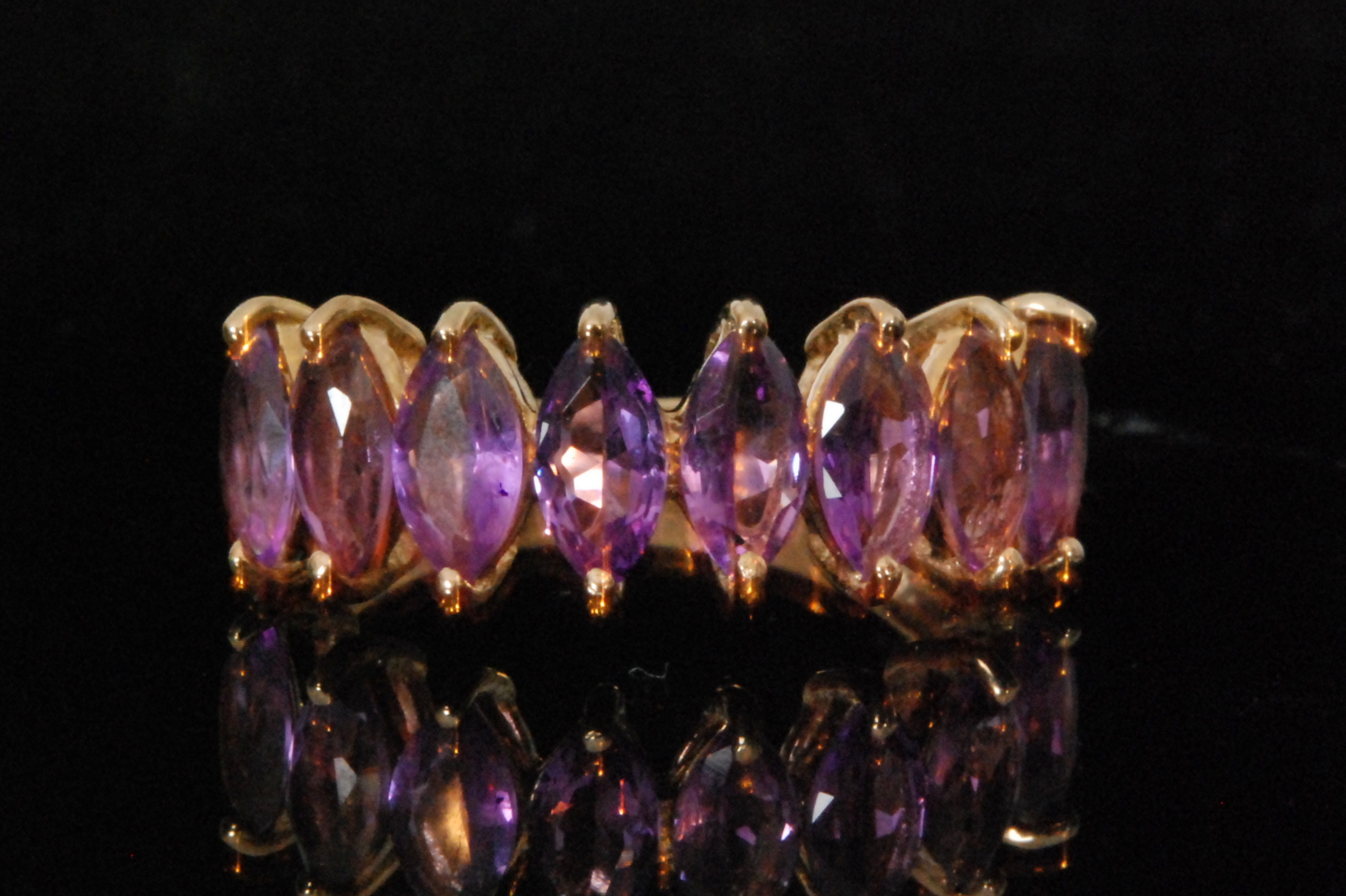 A 9ct amethyst ring comprising of eight marquise claw set stones to plain tapering shoulders,