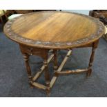 A 20th Century oak gateleg dining table the top carved with a bordered panel of leaves on turned