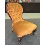A Victorian carved mahogany balloon back easy chair upholstered in gold plush on cabriole legs.