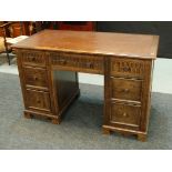 A 20th Century carved oak twin pedestal writing desk the brown leather inset top over a central