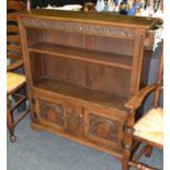 A 17th Century style oak open bookcase the adjustable shelf over a pair of arch panelled doors,