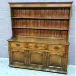 An 18th Century style oak dresser the two tier rack above three drawers and cupboards on a plinth