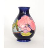 A Moorcroft Magnolia pattern baluster vase decorated with tubelined pink flowers against a blue