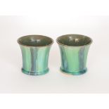 A pair of art pottery beaker vases each decorated in a green glaze with darker streaked panels,