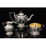 A George V hallmarked silver bachelors tea service comprising pedestal tea pot, cream jug and sugar,