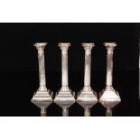 A set of four hallmarked silver Corinthian column candlesticks of typical form terminating in