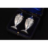 A cased pair of hallmarked silver pepper pots,