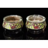 A pair of Russian silver open circular salts with enamelled green leaf and red berry decoration,