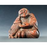 CHINESE BAMBOO CARVING OF BUDDHA OF DA MO. Nineteenth century. Seated figure with a beast biting his