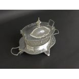 Silver plated and cut glass butter dish of oval form, the lid fitted with a pagoda finial, upon a