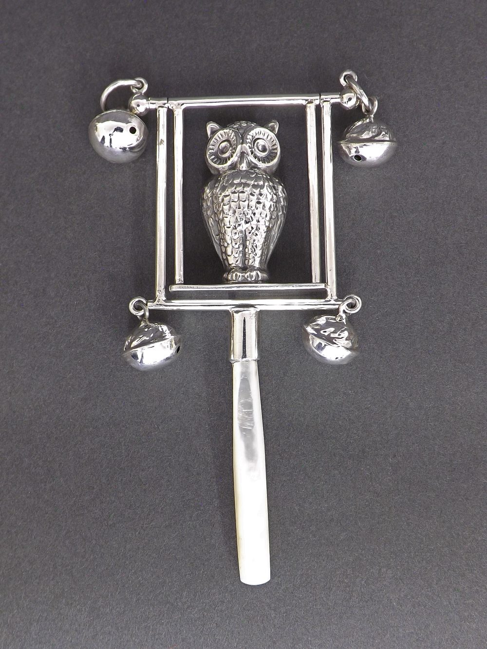 White metal pearl handled novelty baby's rattle in the form of an owl on a swing, 5" long