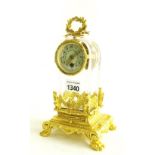 Small unusual ormolu and glass mantel clock timepiece, the 1.75" cream dial within a rounded