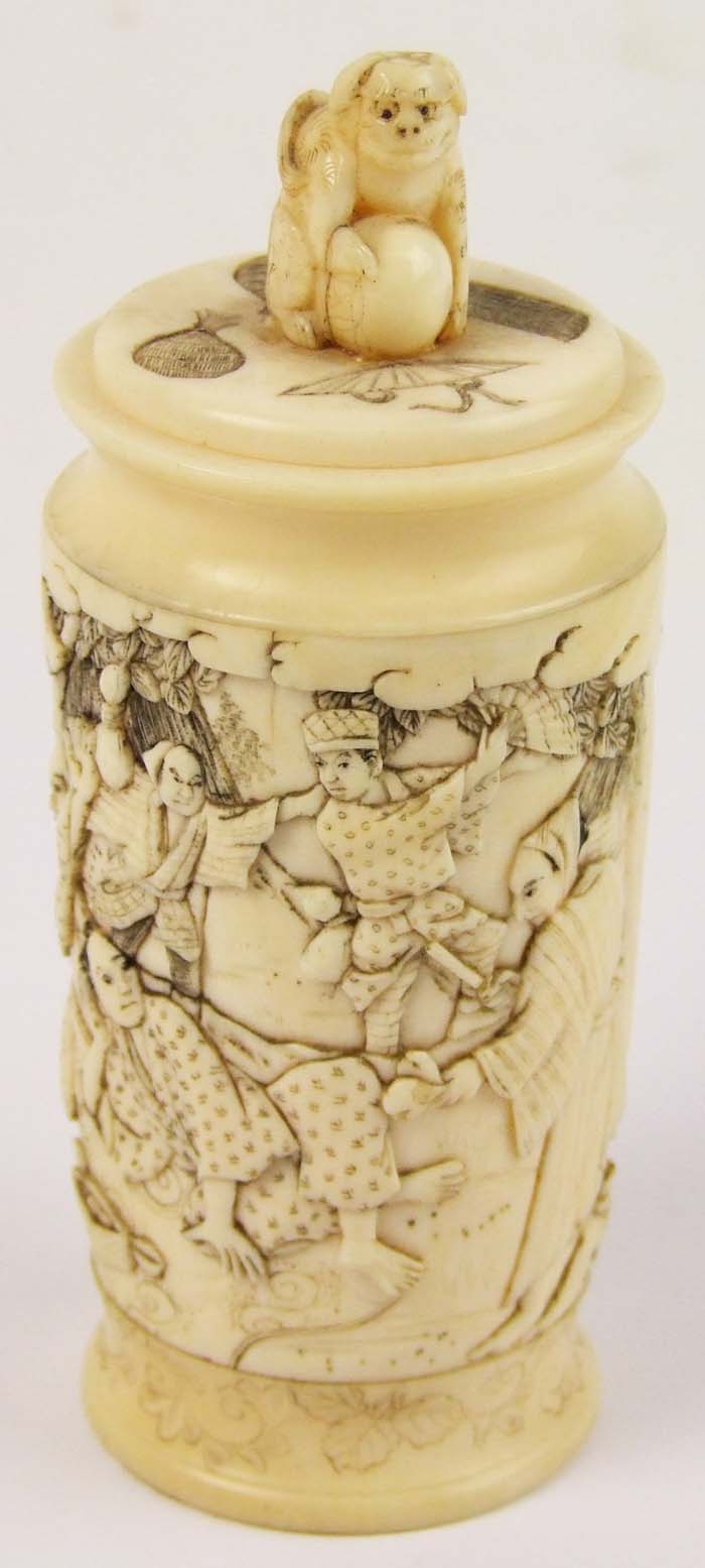 A Japanese carved ivory cylindrical box, the cover with monkey finial, and carved all round with