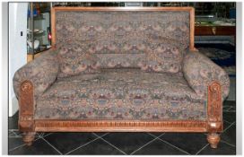 A Large Upholstered Club Type Settee with rolling upholstered arms & back. With a carved oak frame