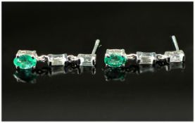 Pair of Emerald Drop Earrings, an oval cut emerald suspended below two baguette cut white topaz in
