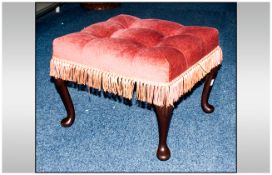 Footstool with pink buttoned upholstery and tassled edging.