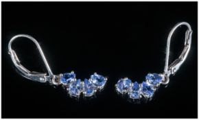 Pair of Tanzanite Drop Earrings, four pear cut tanzanites form a crescent of opposing curve to
