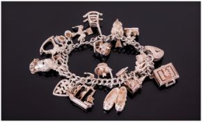 Silver Charm Bracelet Loaded With 16 Charms Complete With Padlock And Saftey Chain.