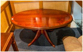 Reproduction Oval Topped Coffee Table with cross Banded edge on pedestal base, terminating on four