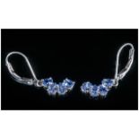 Pair of Tanzanite Drop Earrings, four pear cut tanzanites form a crescent of opposing curve to