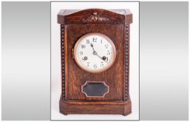 German Oak Cased Mantle Clock in the 1920's style with a round steel dial and exposed pendulum