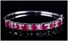 Ruby and White Topaz Bangle comprising a lavish row of seven round cut, rich red, rubies, the
