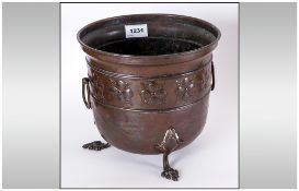 Brass Plant Pot In The Art Nouveau Style, embossed with flower heads to the side on cast brass paw