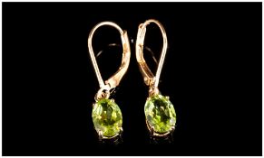 Pair of Peridot Drop Earrings, each comprising an oval cut solitaire peridot set in a 14ct gold