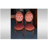 A Pair of French Beech Walnut Stained Music Chairs with a carved medallion button back and pink