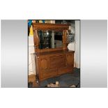An Edwardian Golden Oak Mirrored Back Sideboard with a shaped bevelled mirror.